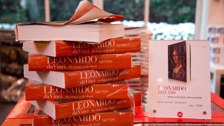 Stacks of red Leonardo da Vinci books beside an upright display copy in the Cenacolo Vinciano museum shop.
