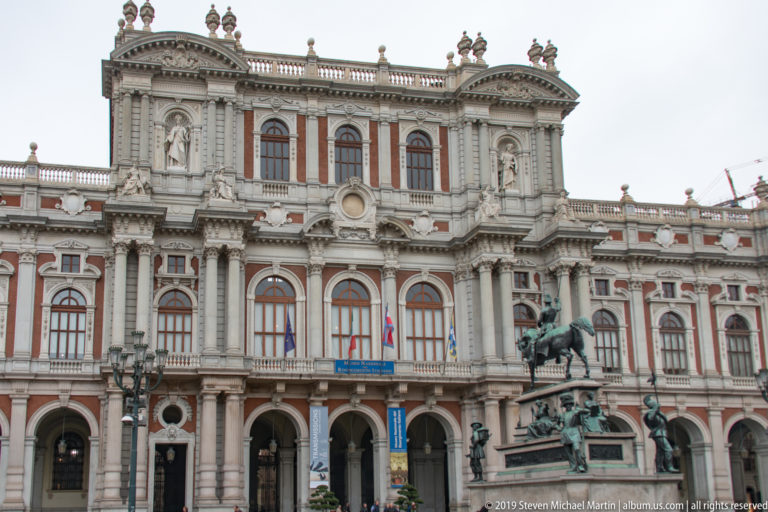 Oblique view of Palazzo Madama’s ornate façade with an equestrian monument at lower right.