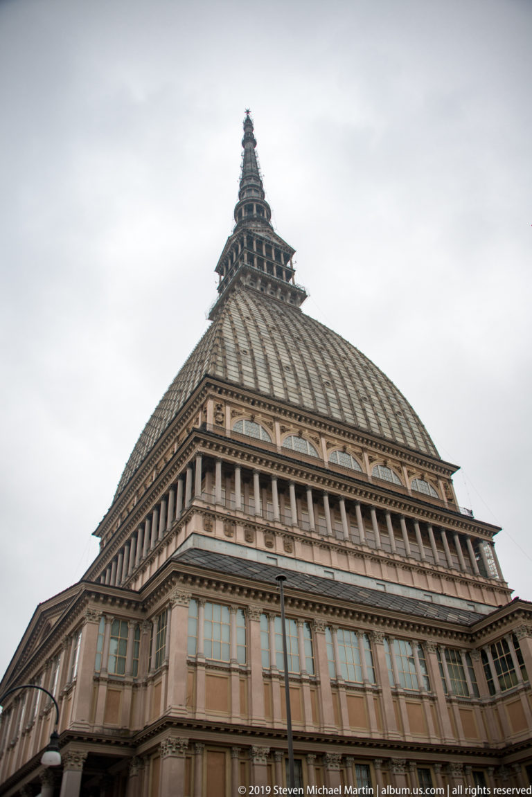 Low-angle view of the Mole Antonelliana showing its vast ribbed roof, windowed base, and tapering tower.