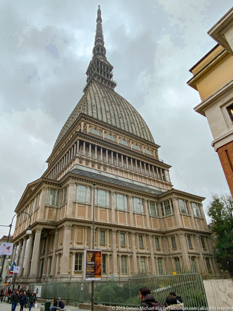 Low-angle view of the Mole Antonelliana showing its monumental base, ribbed dome, and tall tapering spire.