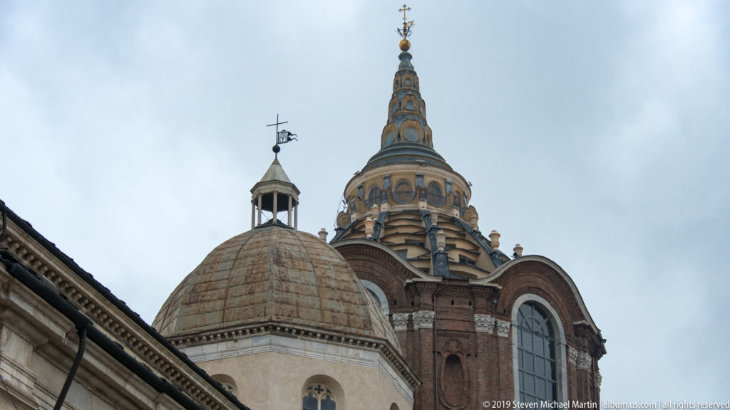 Close exterior view of the Chapel of the Holy Shroud dome and lantern rising behind a smaller neighboring dome.