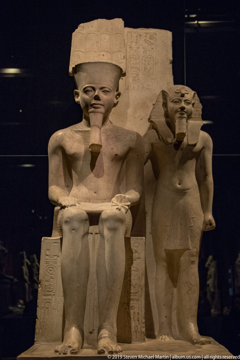 Monumental seated Egyptian king with a smaller standing royal figure beside the throne and hieroglyphic inscriptions.