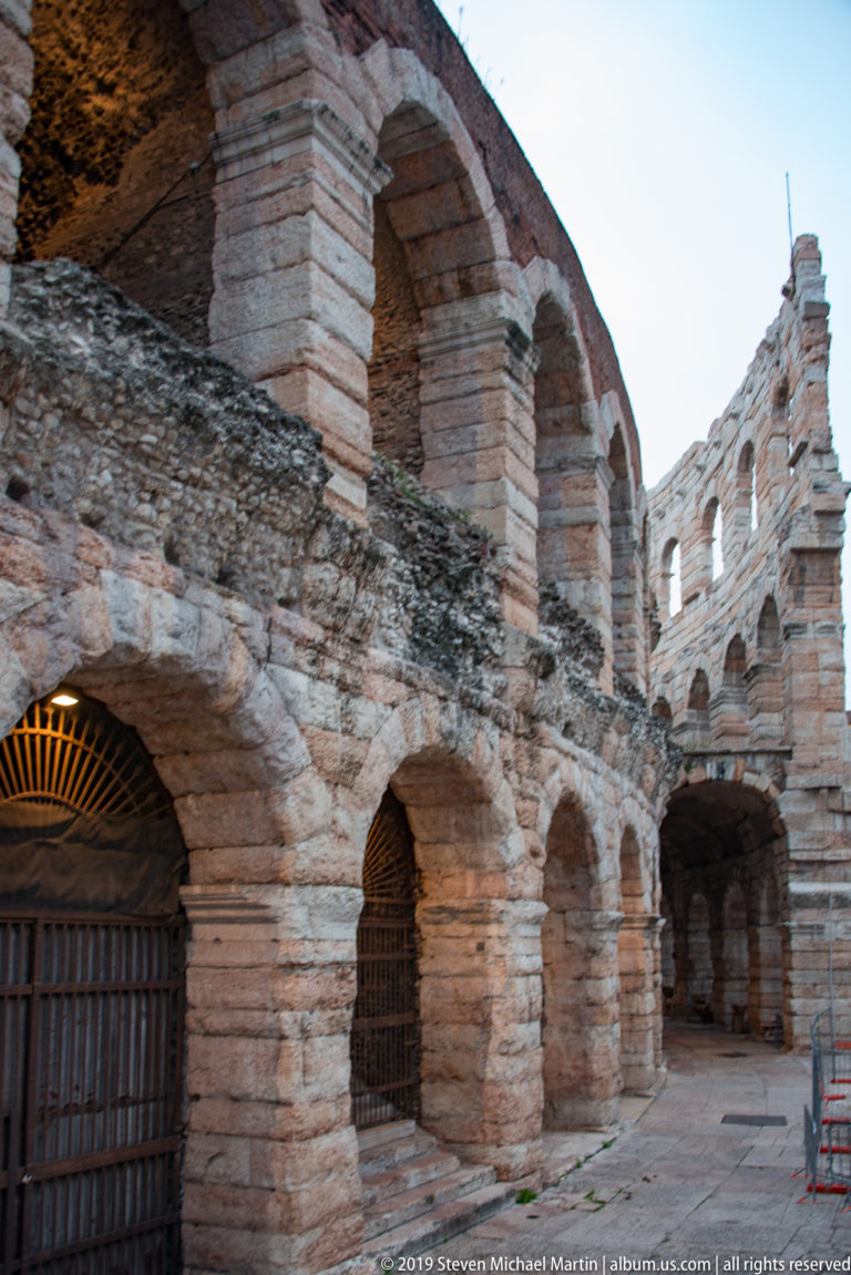 Close exterior view of Arena di Verona with gated lower arches and a second tier of open arcades above.