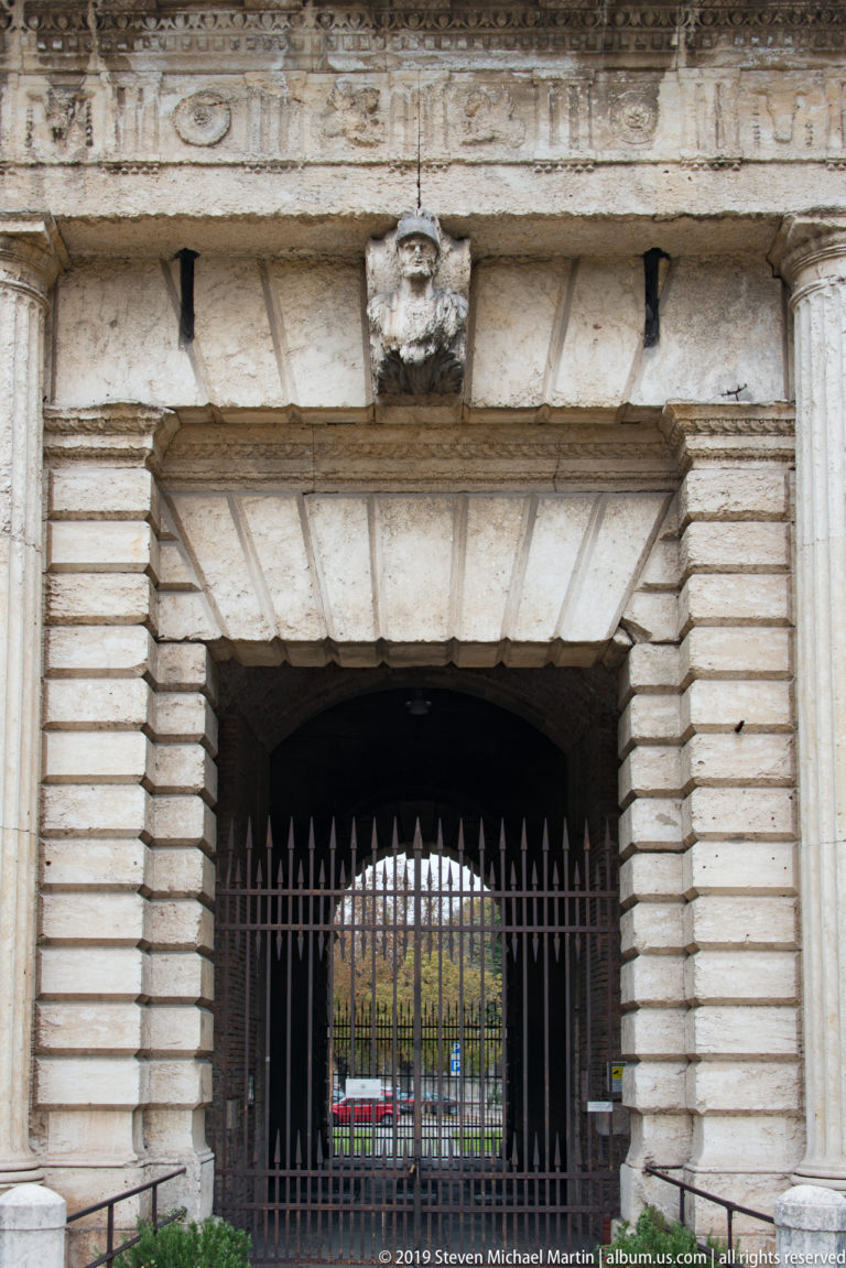 Central passage of Porta Nuova with heavy rusticated stone arch, iron grille, and view through to the far side.