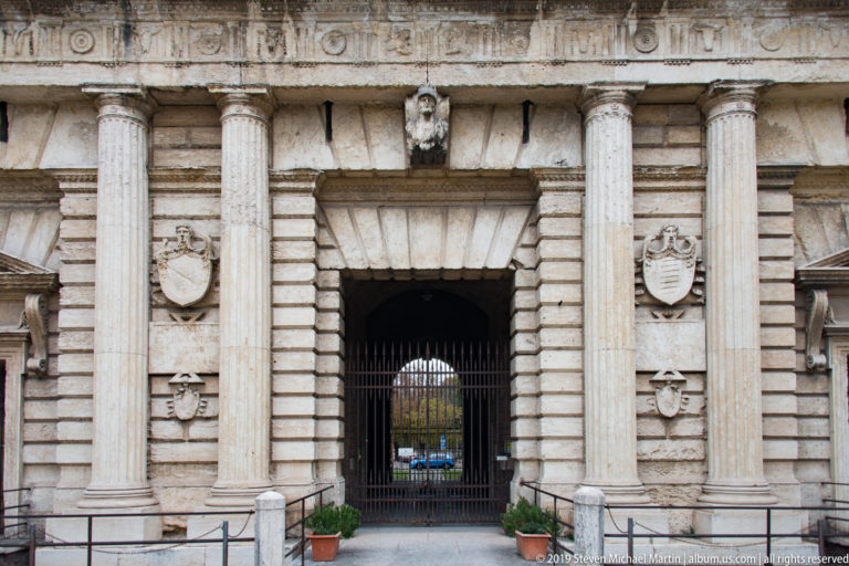 Porta Nuova entrance bay with fluted columns, rusticated stonework, heraldic shields, and a deep gated passage.