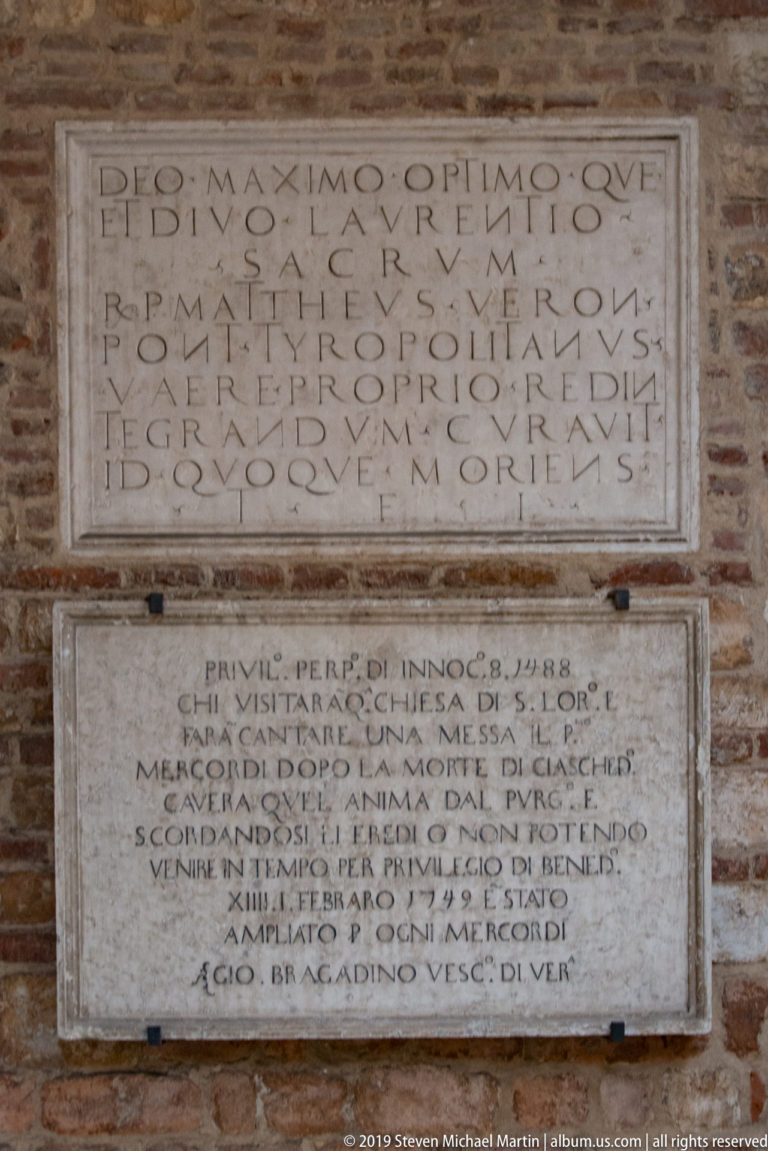 Two Latin-inscribed stone plaques mounted vertically on a brick wall at San Lorenzo.