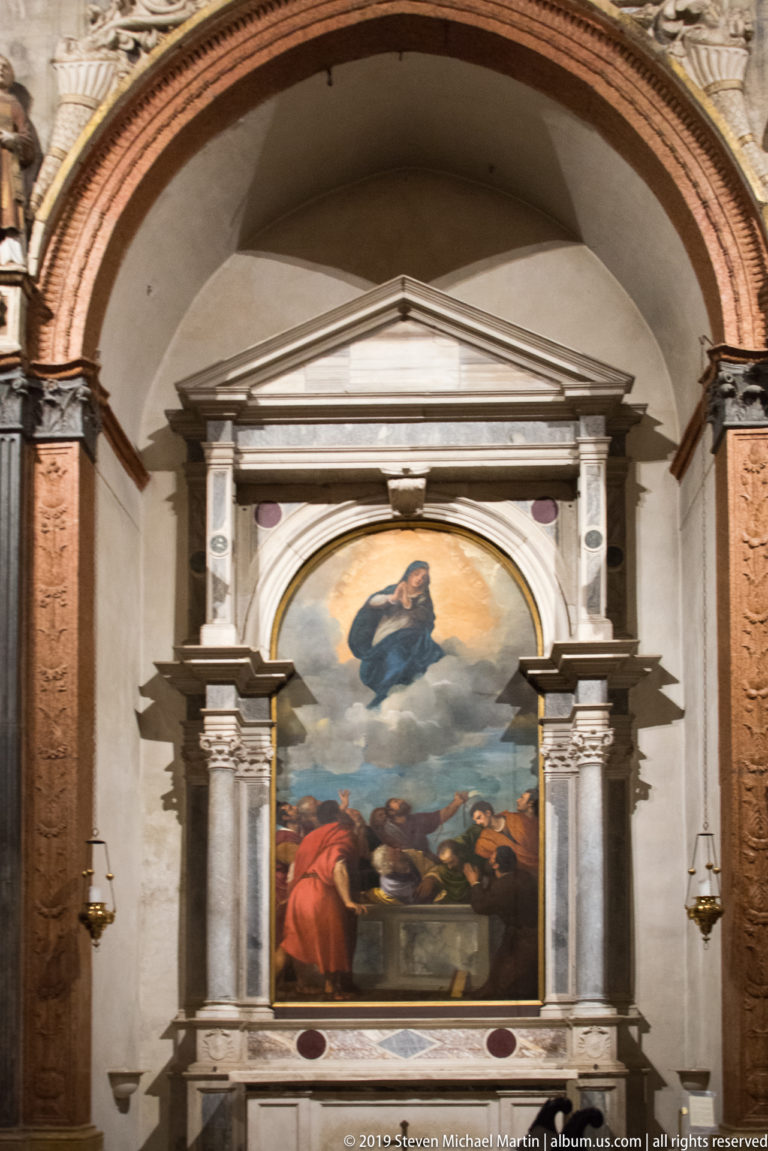 Large religious painting in a side chapel, enclosed by paired supports, pale architectural moldings, and a triangular pediment.