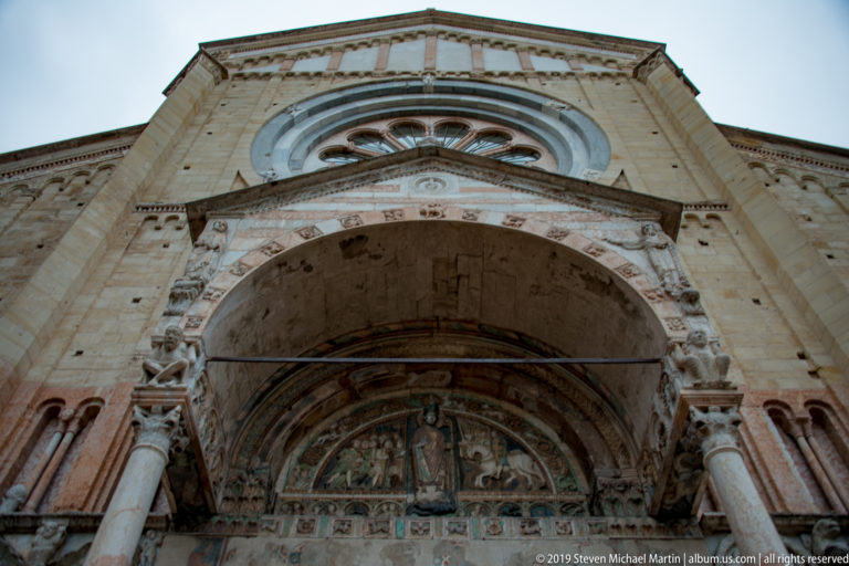 Low-angle view of the main portal with carved columns, sculpted surround, and painted imagery inside the deep arch.