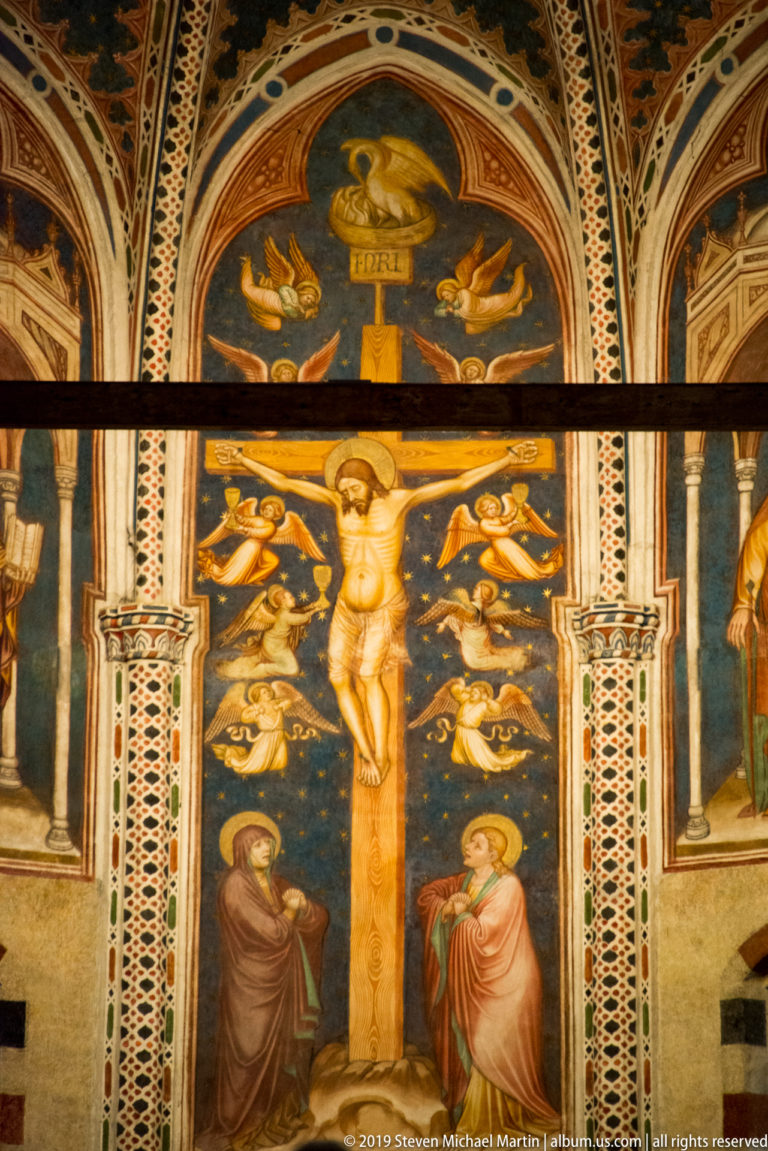 Fresco of the Crucifixion with Christ, mourners, many angels, and ornate painted borders.