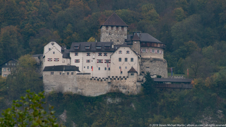Gutenberg Castle on a wooded rocky hill, with pale walls and a tall square tower above Balzers.