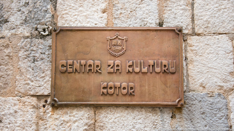 Bronze plaque reading “Centar za Kulturu Kotor” with a municipal crest mounted on pale stone.