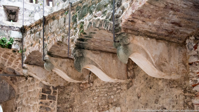 Row of large projecting stone corbels beneath weathered masonry and brick inside Kotor’s fortifications.