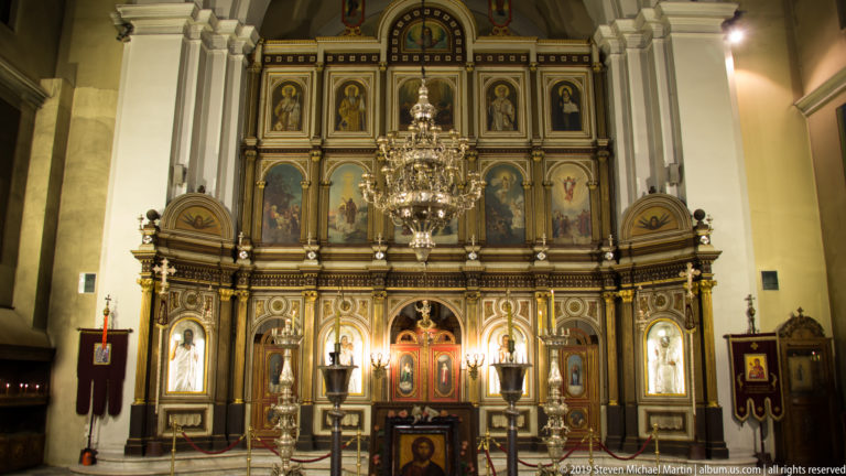 Symmetrical frontal view of the multi-tier painted iconostasis and central chandelier in St. Nicholas Church, Kotor.