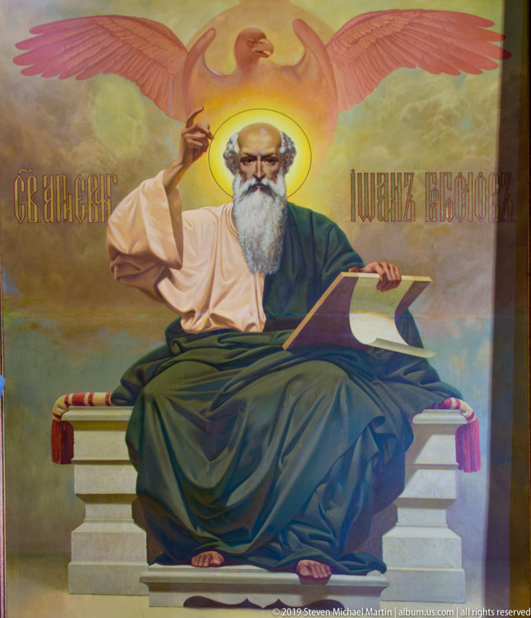Mural of St. John seated with writing material and an eagle above, inside St. Nicholas Church in Kotor.