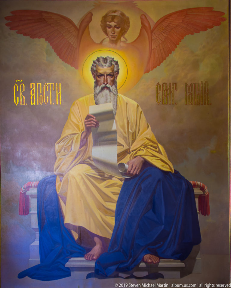 Mural of St. Matthew seated with a scroll, with a winged human figure above, inside St. Nicholas Church in Kotor.