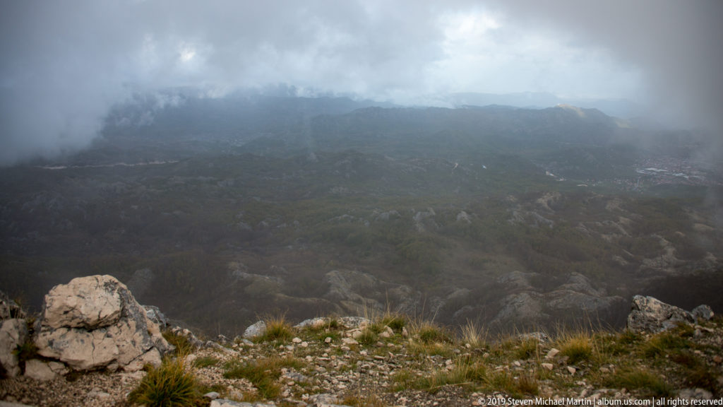 Fog hangs over broken limestone and sparse highland vegetation on Lovćen near the Njegoš Mausoleum in Montenegro.