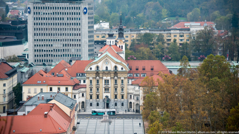 Elevated view over red roofs to the Ursuline Church of the Holy Trinity, with modern towers behind.
