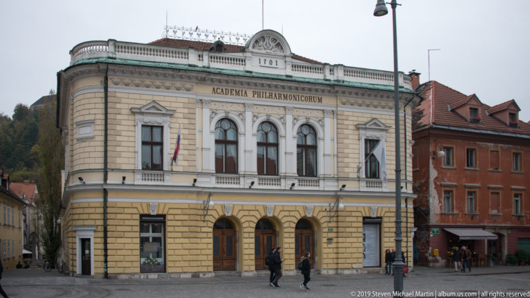 Historic Slovenian Philharmonic façade with arched windows and the inscription ACADEMIA PHILHARMONICORUM.