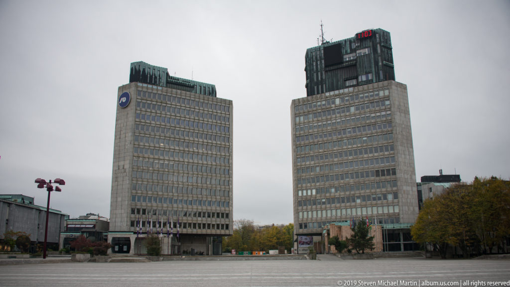 Two tall modernist office towers rising behind the broad paved expanse of Republic Square in Ljubljana.