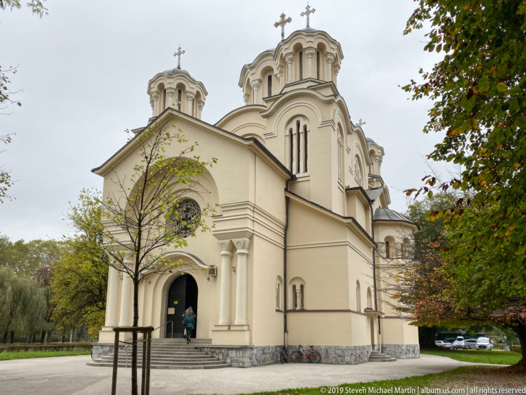 Closer angled view of the Church of Saints Cyril and Methodius with arched entrance, rounded towers, and crosses.