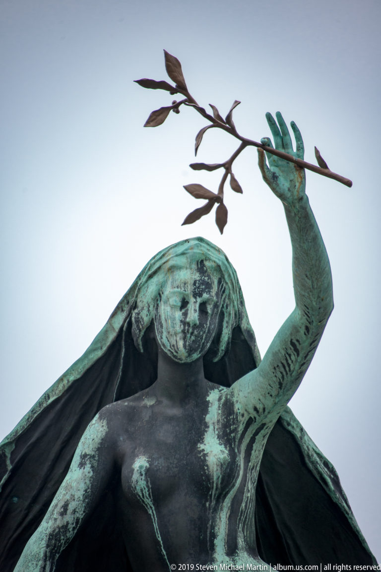 Low-angle close-up of the bronze female muse figure holding a laurel branch above the Prešeren Monument.