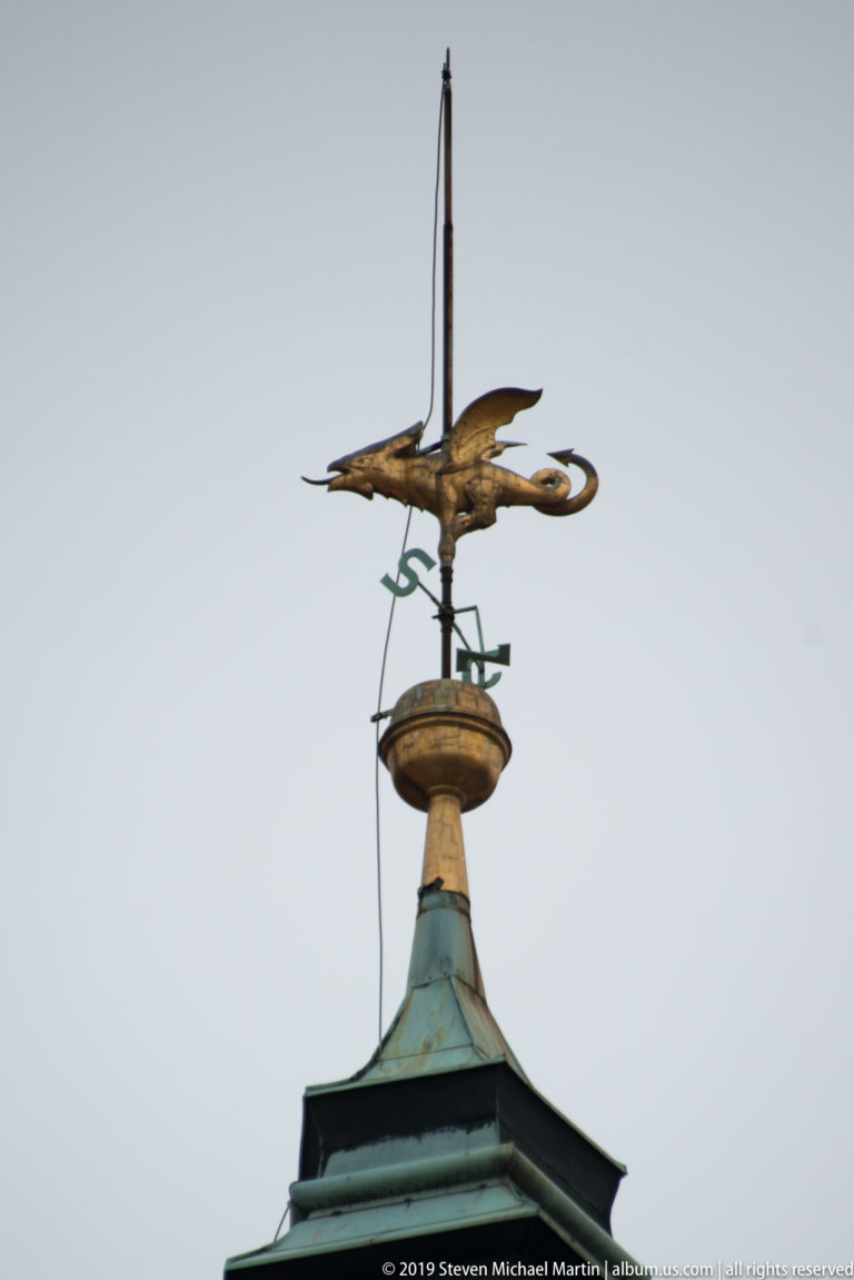 Golden dragon-shaped weather vane mounted above the green copper roof of Ljubljana Town Hall.
