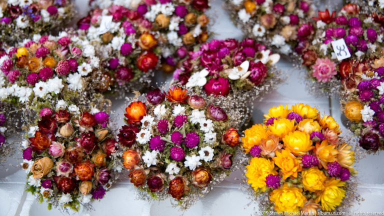 Colorful dried-flower wreaths and small bouquets arranged across a market table.