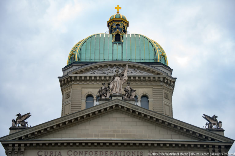 Upper façade and green dome of the Federal Palace with sculptural roof ornament.