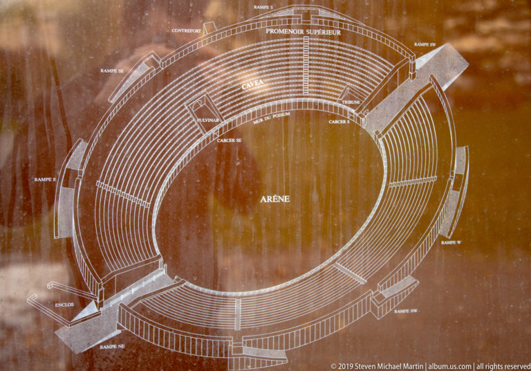 Architectural plan of an elliptical amphitheatre labeled with arena, cavea, promenades, entrances, and ramps.
