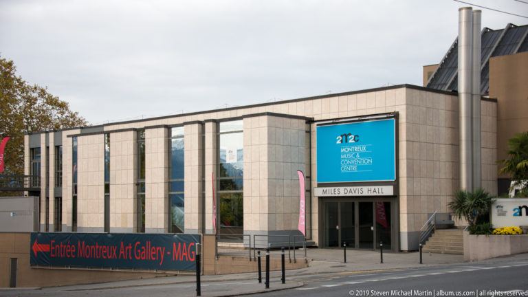 Modern stone-and-glass entrance marked “Miles Davis Hall,” with Montreux Music & Convention Centre signage.