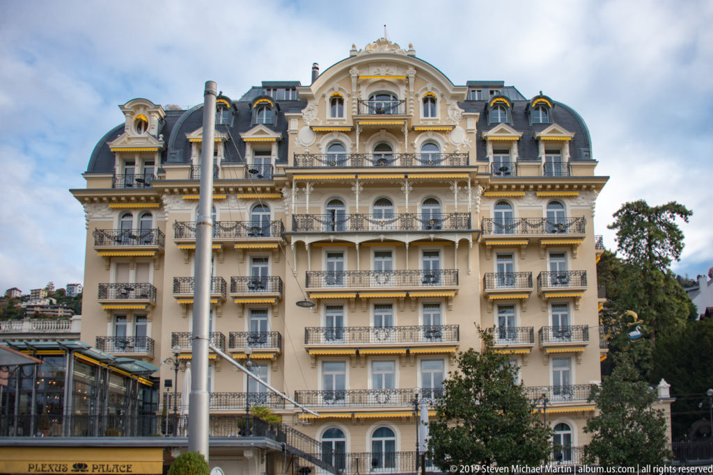 Grand cream-colored Montreux Palace hotel with balconies, central gable, dormers, and dark mansard roof.