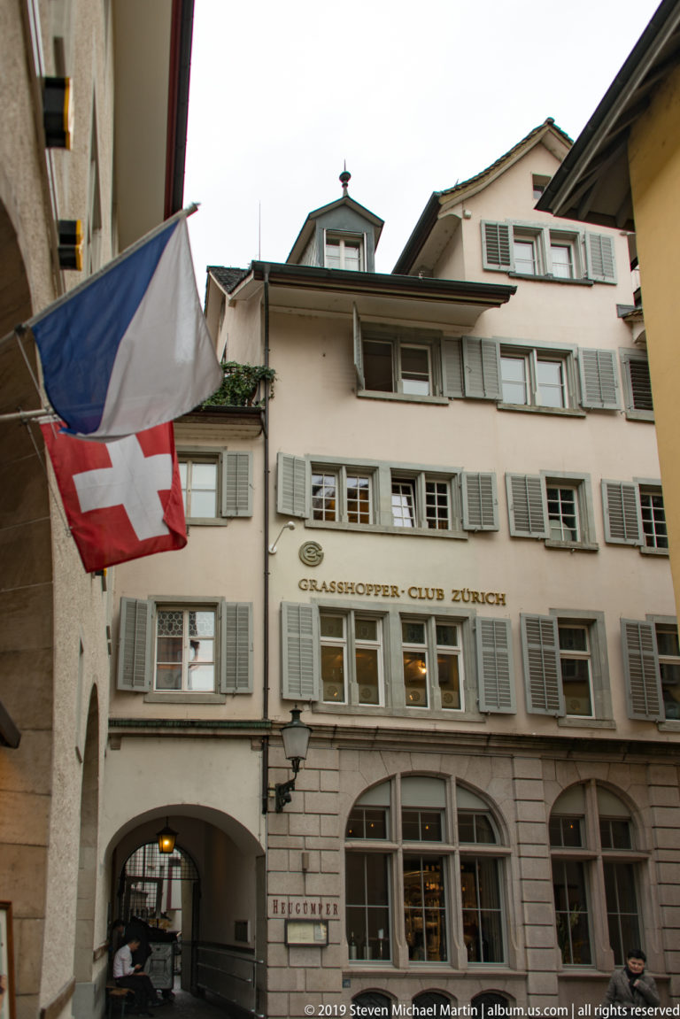 Grasshopper-Club Zürich façade with shuttered windows, arched ground-floor openings, and flags projecting in the foreground.