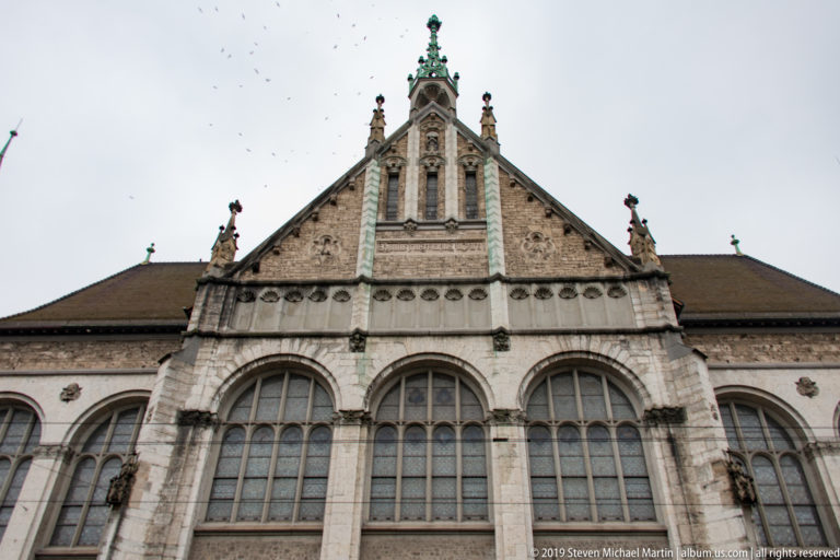 Ornate Swiss National Museum gable with pinnacles, sculptural figures, circular motifs, and three large arched windows.