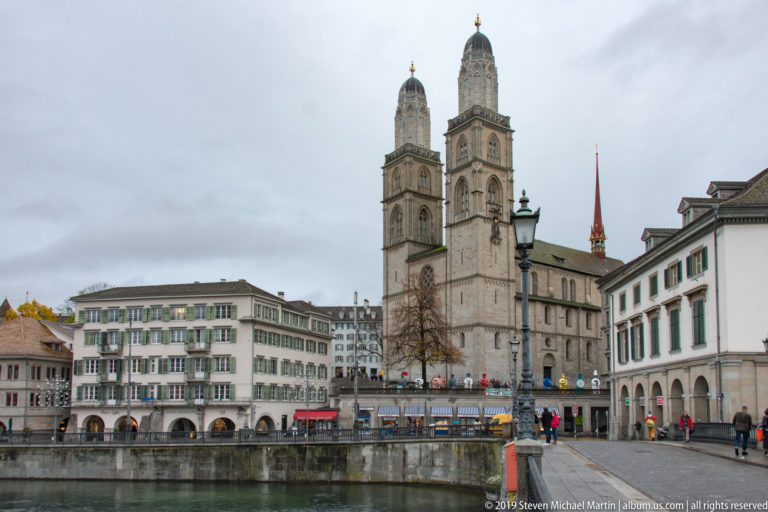 Twin Grossmünster towers rising above the church and riverfront buildings across the Limmat in Zurich.