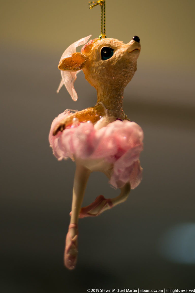 Small deer figurine posed as a ballerina in a pink tutu and ballet slippers.