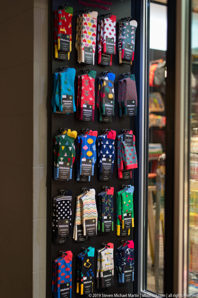 Rows of colorful patterned socks arranged in a brightly lit Zurich shop window.