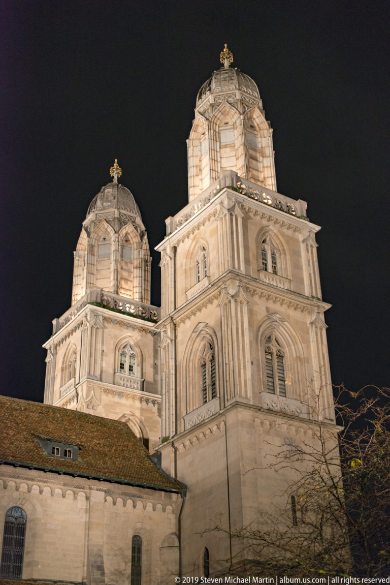 Close low-angle night view of the illuminated twin stone towers of Zurich’s Grossmünster.