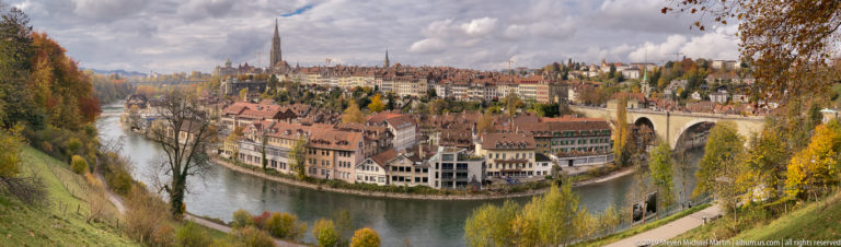 Panoramic view of Bern’s Old City inside a bend of the Aare, with a high stone bridge.