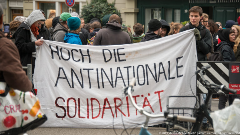 Protesters in Bern holding a large banner reading “HOCH DIE ANTINATIONALE SOLIDARITÄT.”
