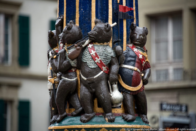 Cluster of small painted armored bears around a blue-and-gold fountain column in Bern.