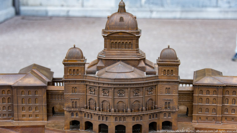 Bronze-toned architectural model of the Swiss Federal Palace with central dome, flanking cupolas, and symmetrical wings.