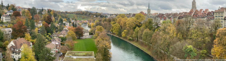 Green Aare River winding between autumn trees and hillside houses below Bern.