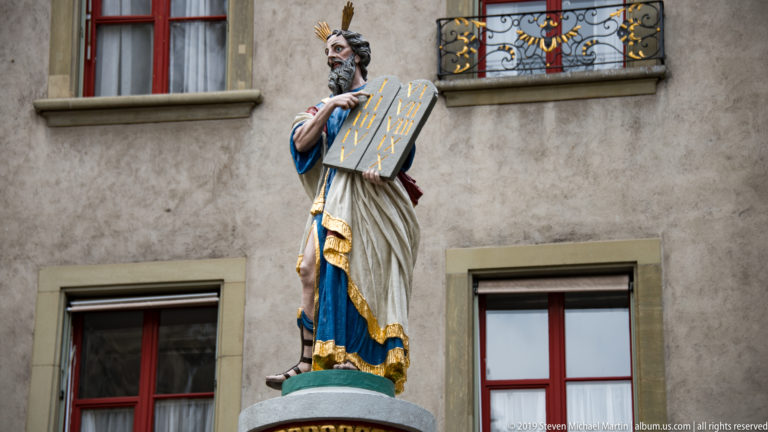 Polychromed statue of Moses holding tablets in front of an Old City building in Bern.