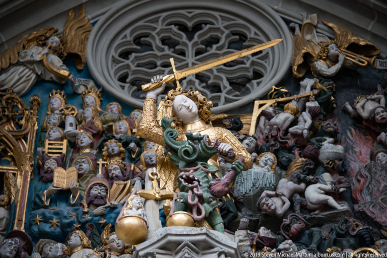 Polychromed Last Judgment scene with Archangel Michael, sword and scales, surrounded by saved and damned figures.