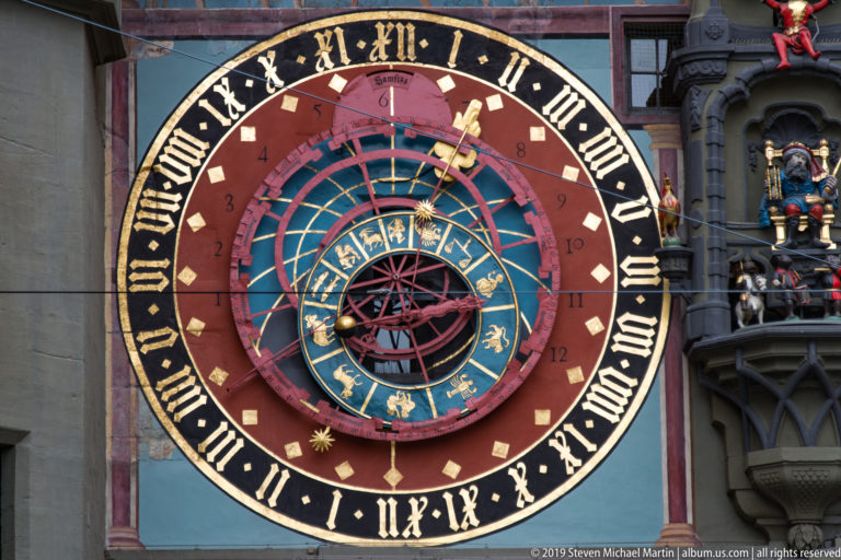 Close view of the Zytglogge astronomical clock with Roman numerals, zodiac ring, and metal pointers.