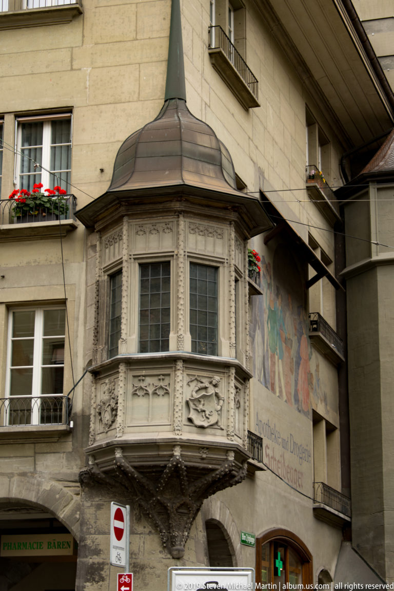 Carved projecting bay window with relief decoration on a painted historic façade in Bern’s Old City.