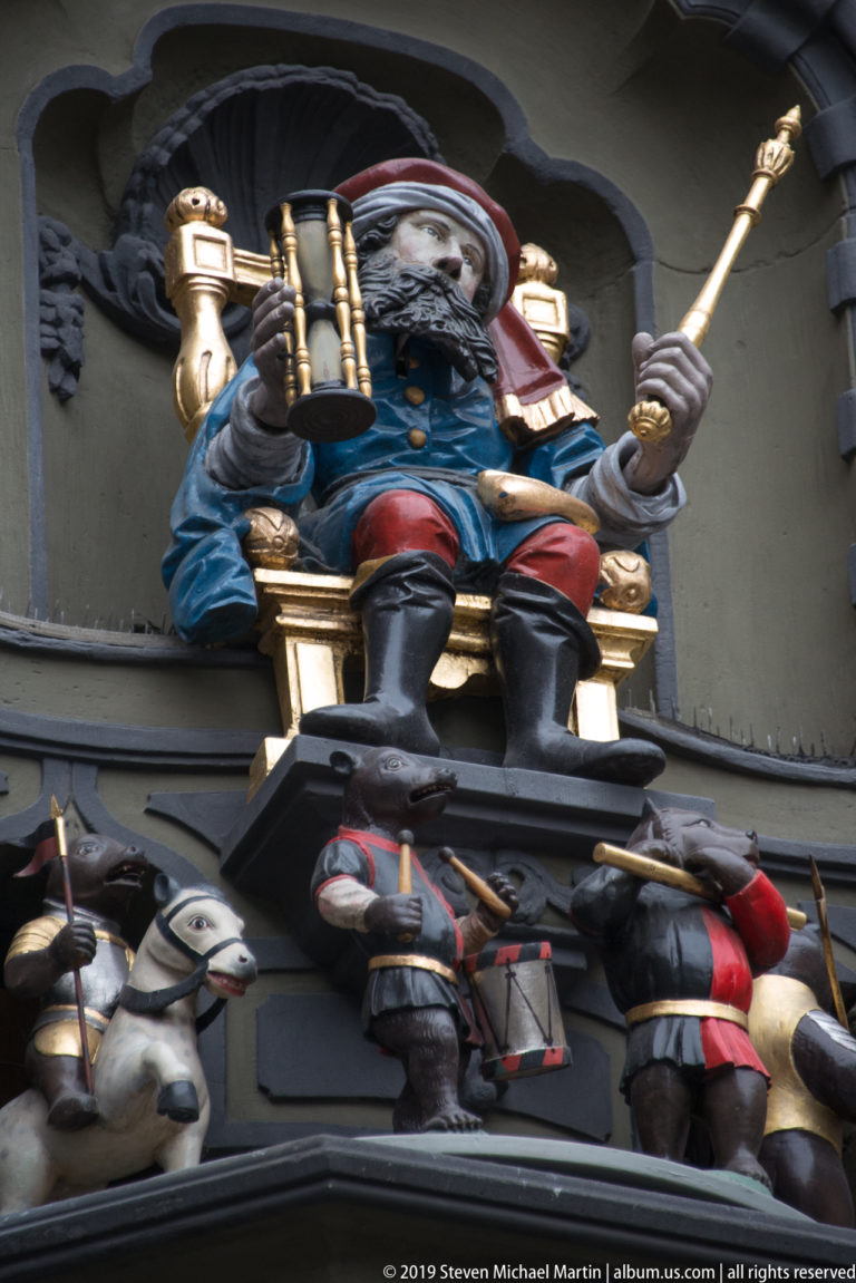 Painted seated automaton with staff above smaller mechanical figures on Bern’s Zytglogge.