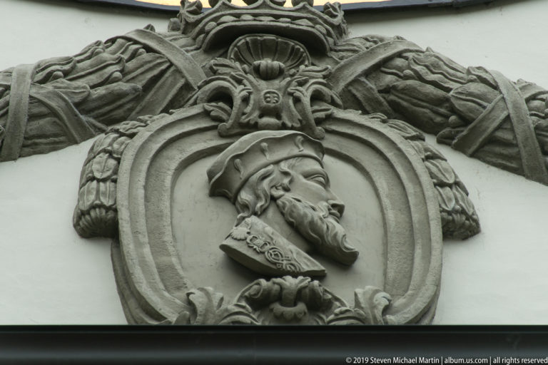 Stone profile relief of a bearded man in a cap within an ornate oval cartouche.
