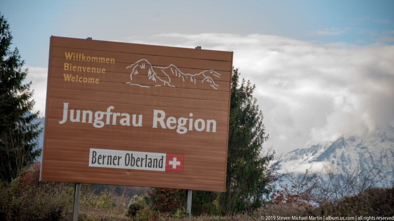 Brown welcome sign reading “Jungfrau Region” and “Berner Oberland” with snowy mountains behind.