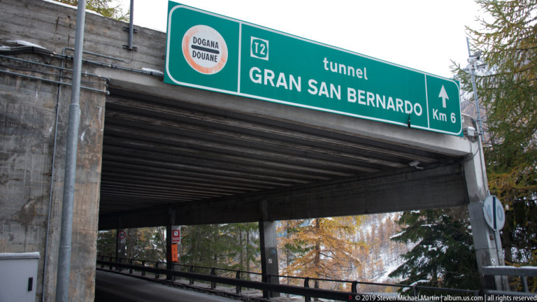 Green road sign reading “tunnel GRAN SAN BERNARDO Km 6” with a Dogana-Douane customs symbol.